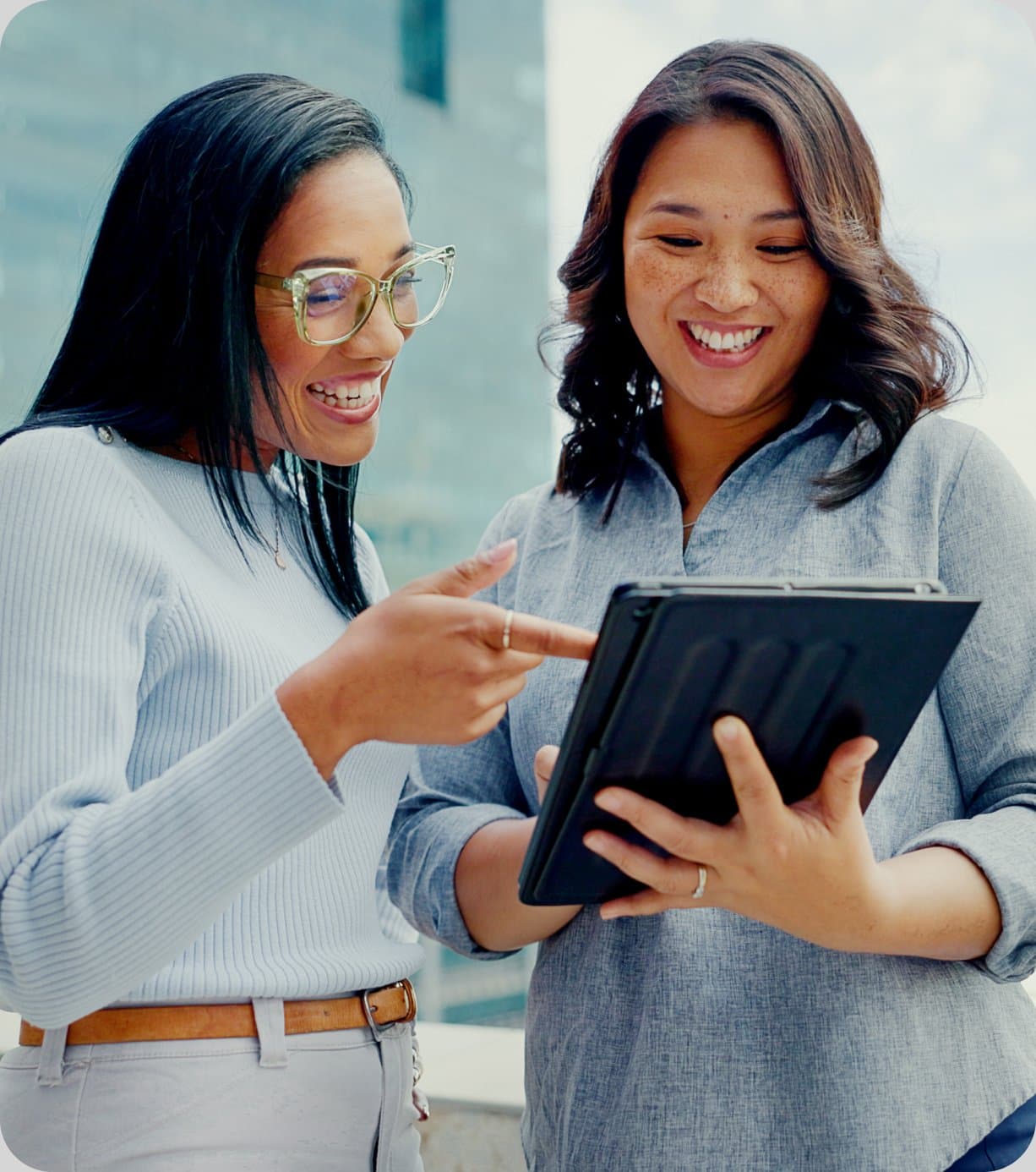 Two colleagues smiling while reviewing details on a tablet